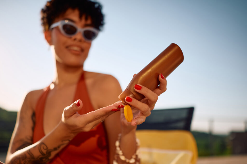 Close up of African American woman applying suntan lotion.