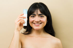 Happy woman showing skincare product, promoting beauty routine and healthy, glowing facial skin